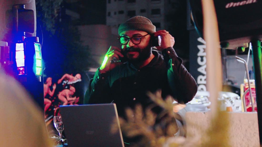 Convidado de óculos iluminado por neon verde e magenta na área externa do evento